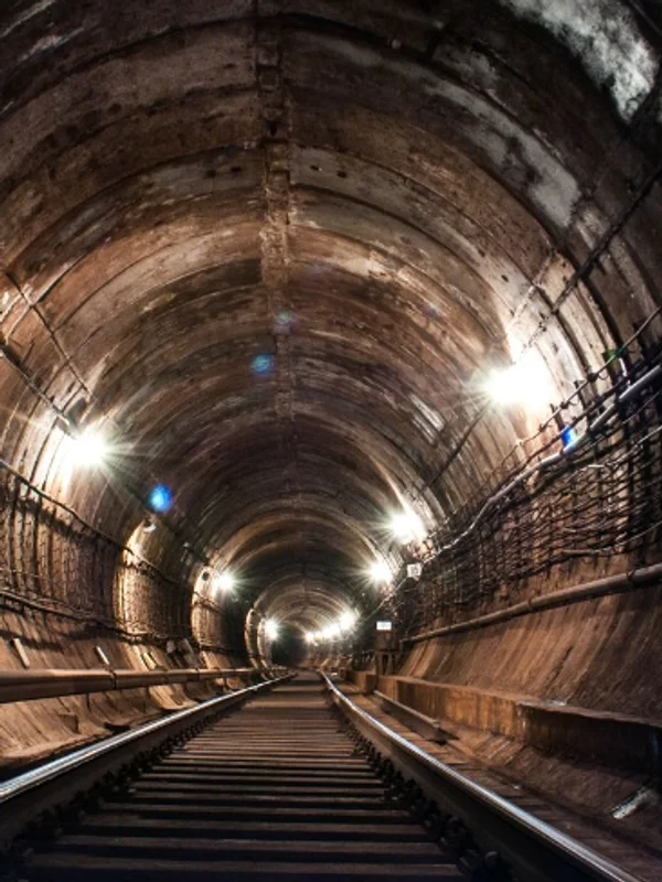 Railway tracks running into a lit tunnel